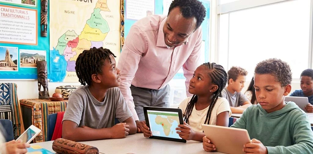 Un enseignant montre la carte du Cameroun sur une tablette à ses élèves