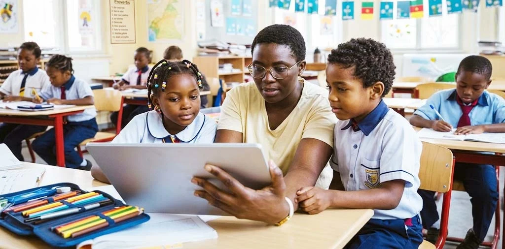 Une enseignante montre une tablette à des écoliers en uniforme