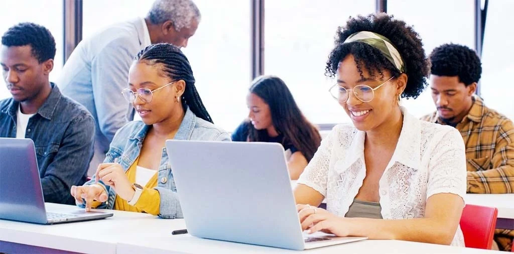 Des étudiants au travail sur ordinateur, accompagnés par un encadrant